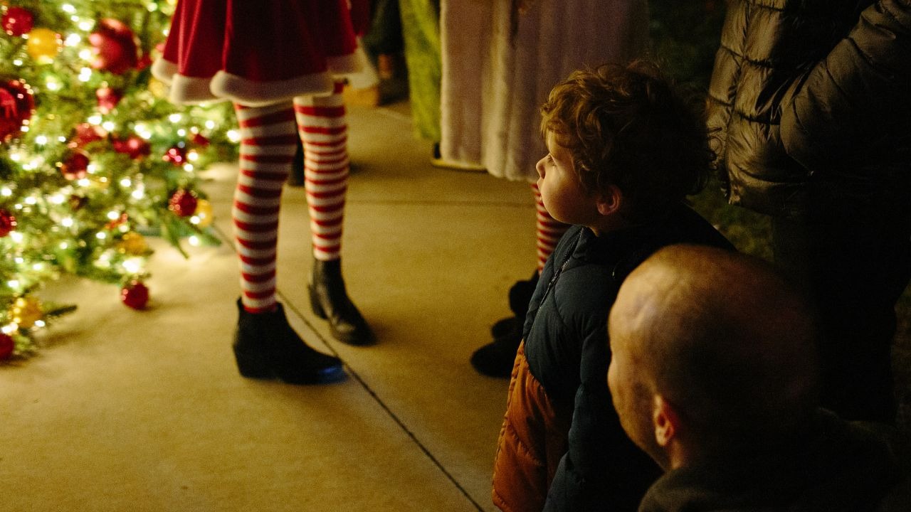 Child admiring a festive Christmas tree at Biltmore Park’s Asheville holiday event.