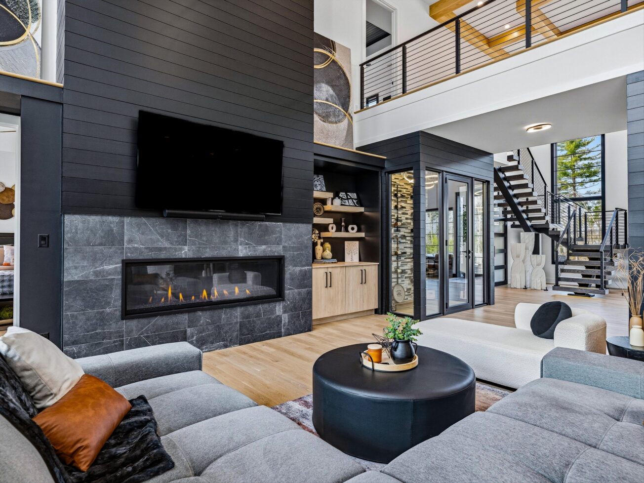 Large grey sectional couch surrounds a black table in front of a fireplace and TV.