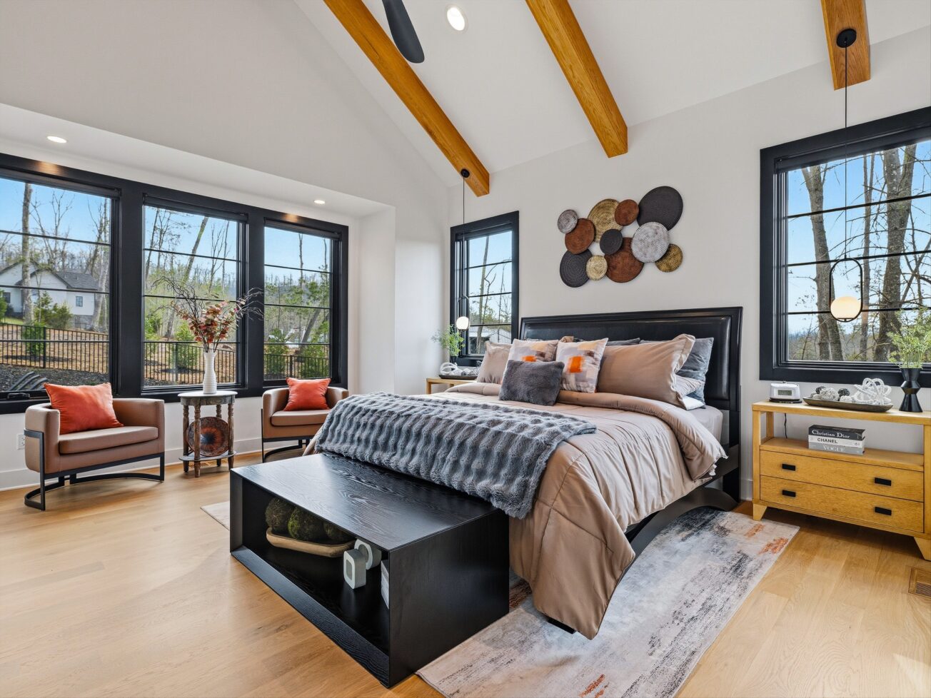 Master bedroom with black bed and large windows.