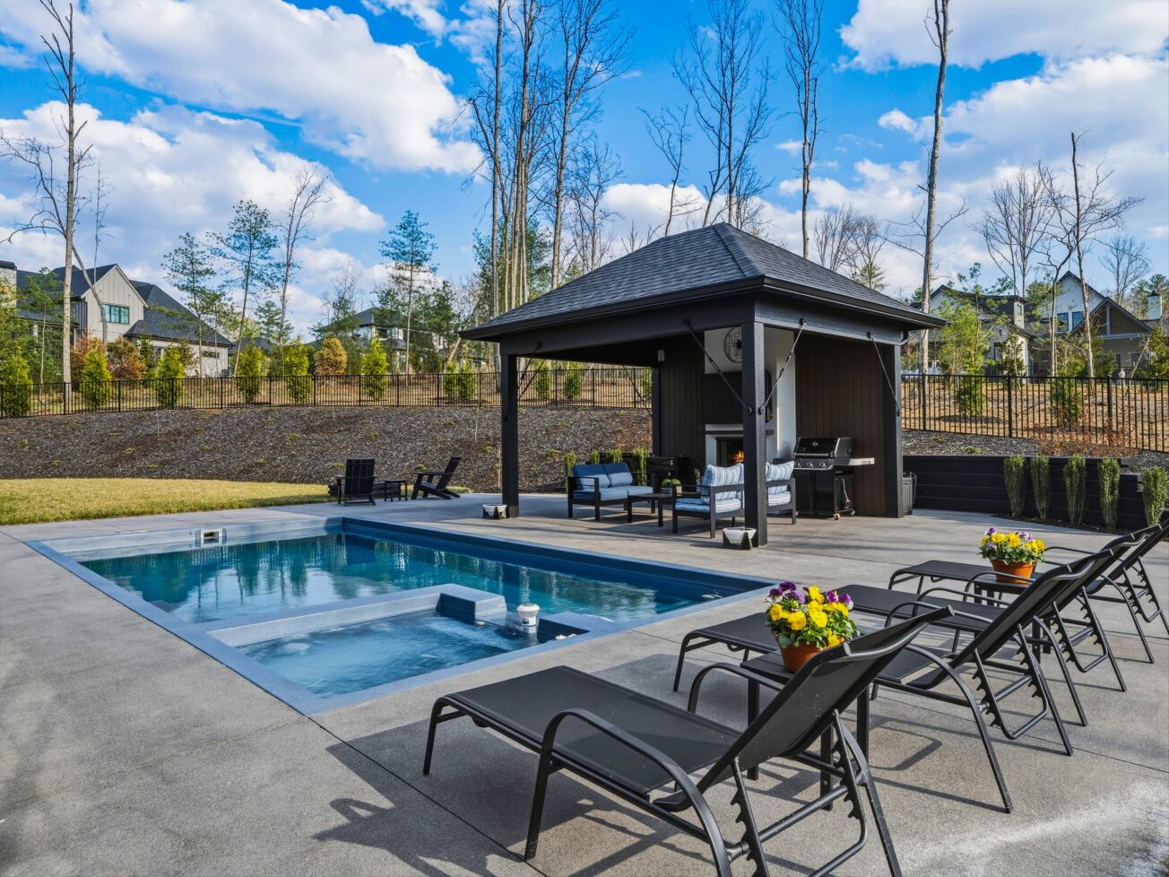 Outdoor pool with pool house and lounge chairs.