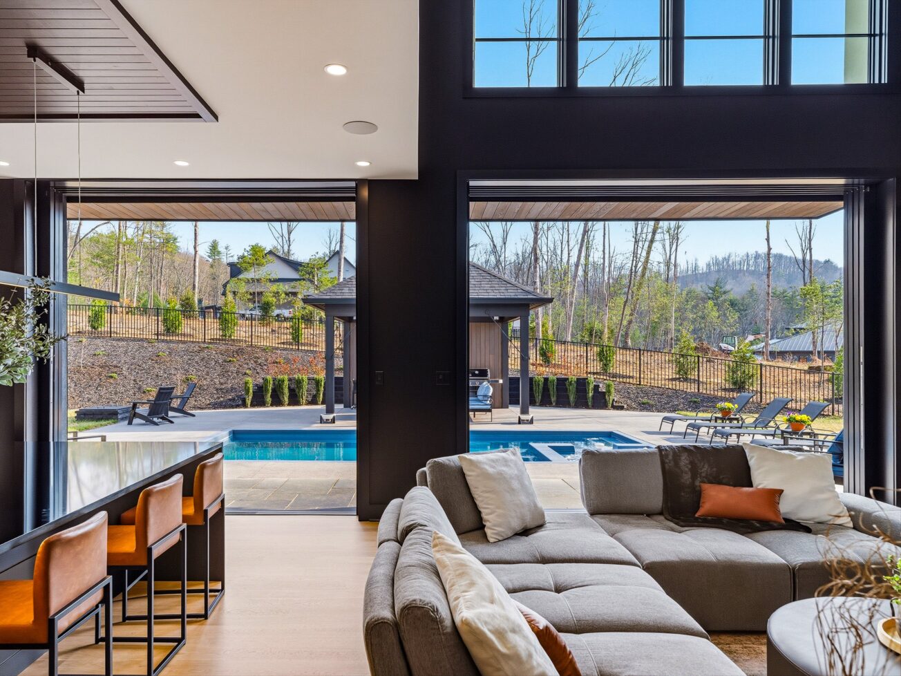 Living room opens to large windows overlooking mountain views and a pool.