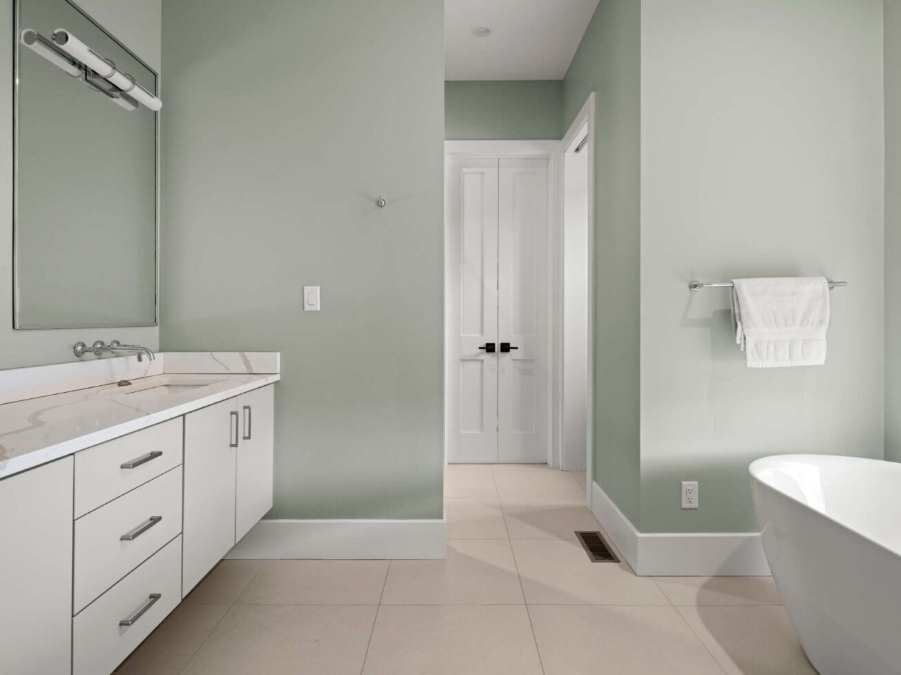 Modern bathroom with white fixtures and pale green walls.