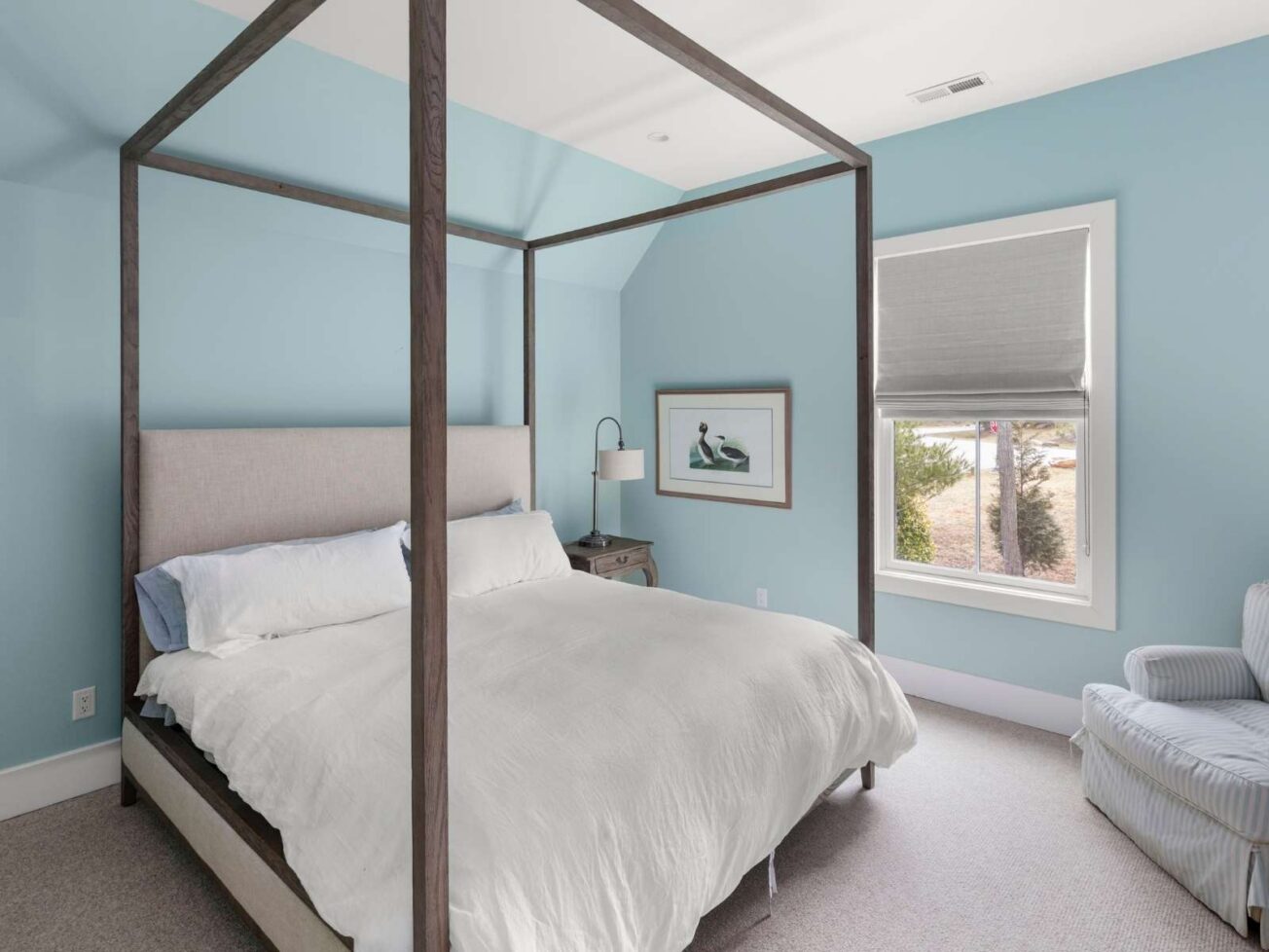 Bed in the middle of a bedroom with light blue walls.